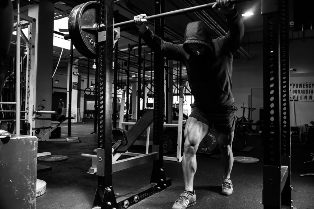 A lifter preparing beneath a loaded barbell in a squat rack.